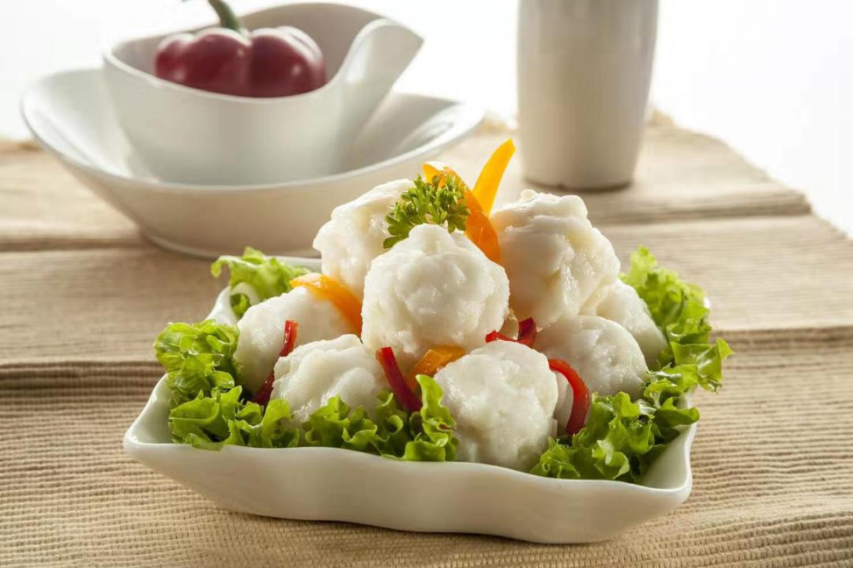 Plated dish of white dumplings with vegetables on a beige tablecloth