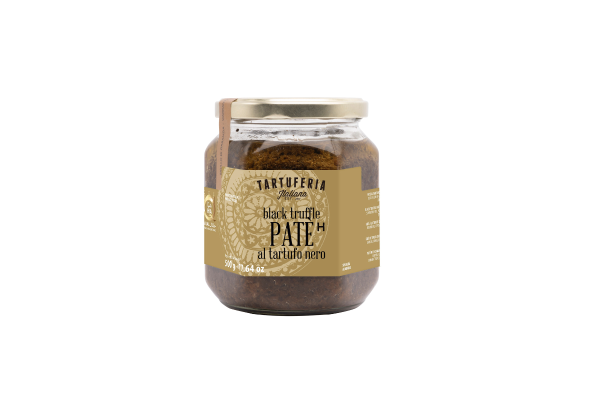Jar of black truffle pate with a gold lid on a white background