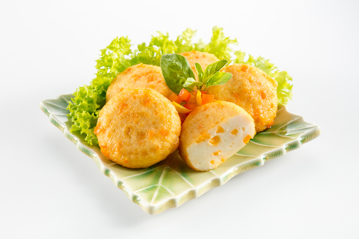 Five round cheese fish tofu on a plate with salad on a white background