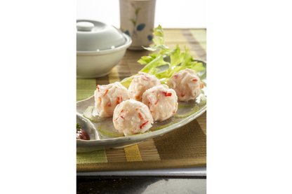 Plated lobster ball on a bamboo mat with a bowl in the background