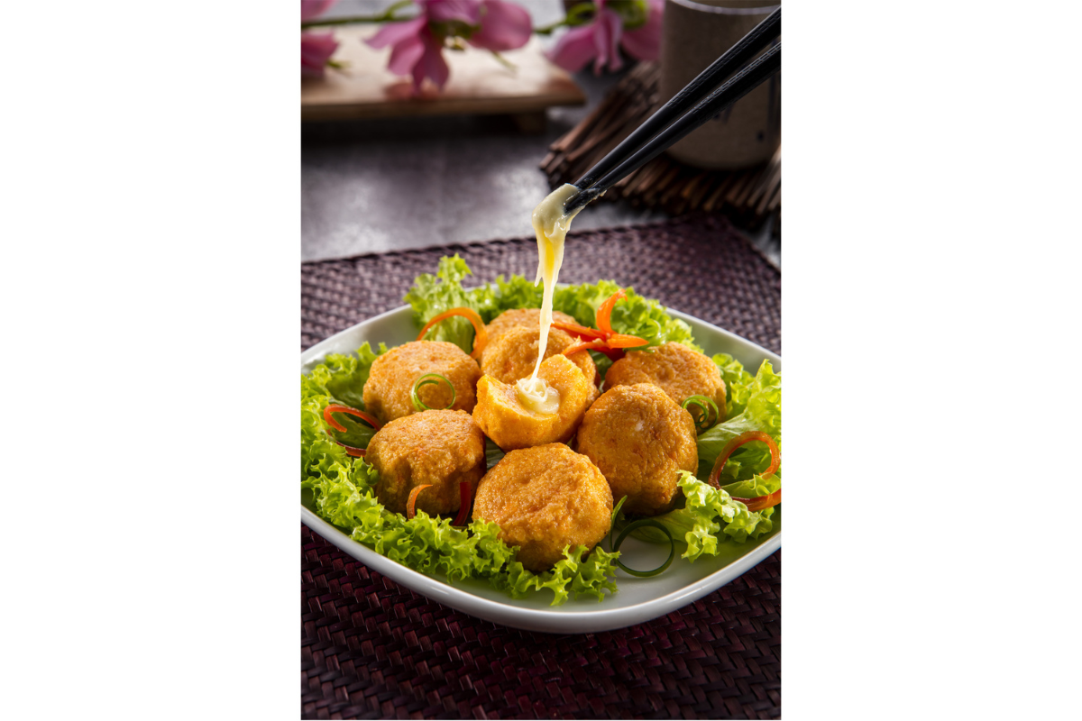 Dish of fried balls on a bed of lettuce with cheese, served on a white plate.