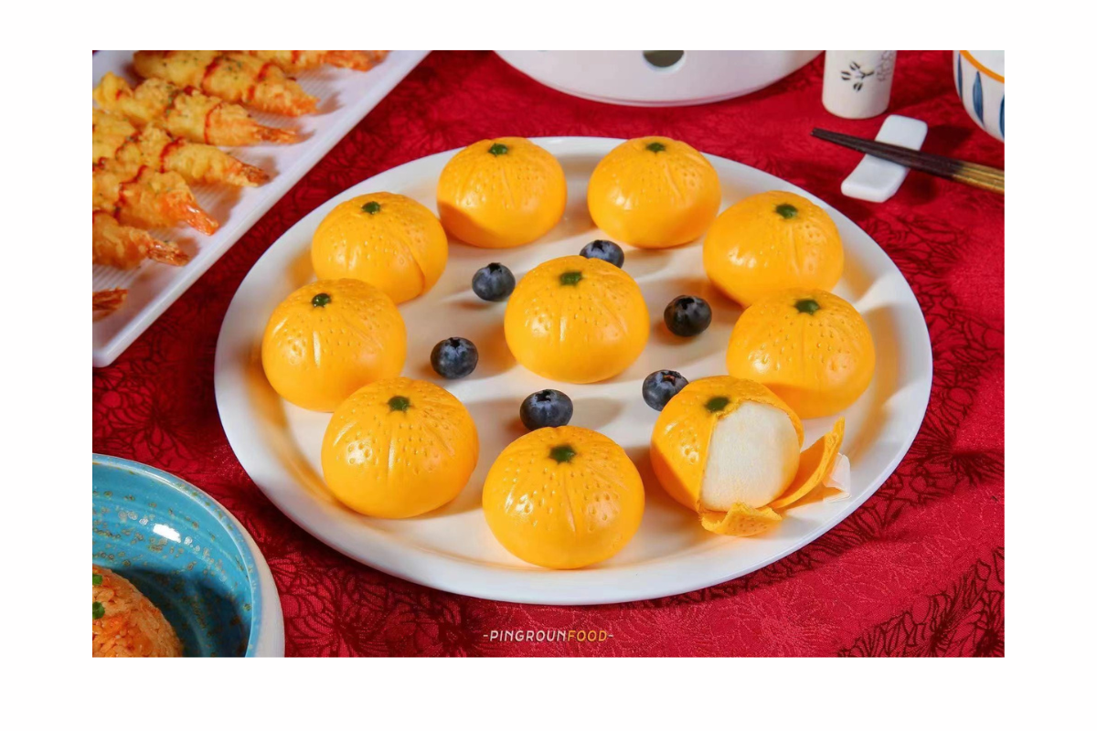 Decorative plate with tangerine buns on a red tablecloth.