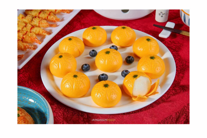 Decorative plate with tangerine buns on a red tablecloth.