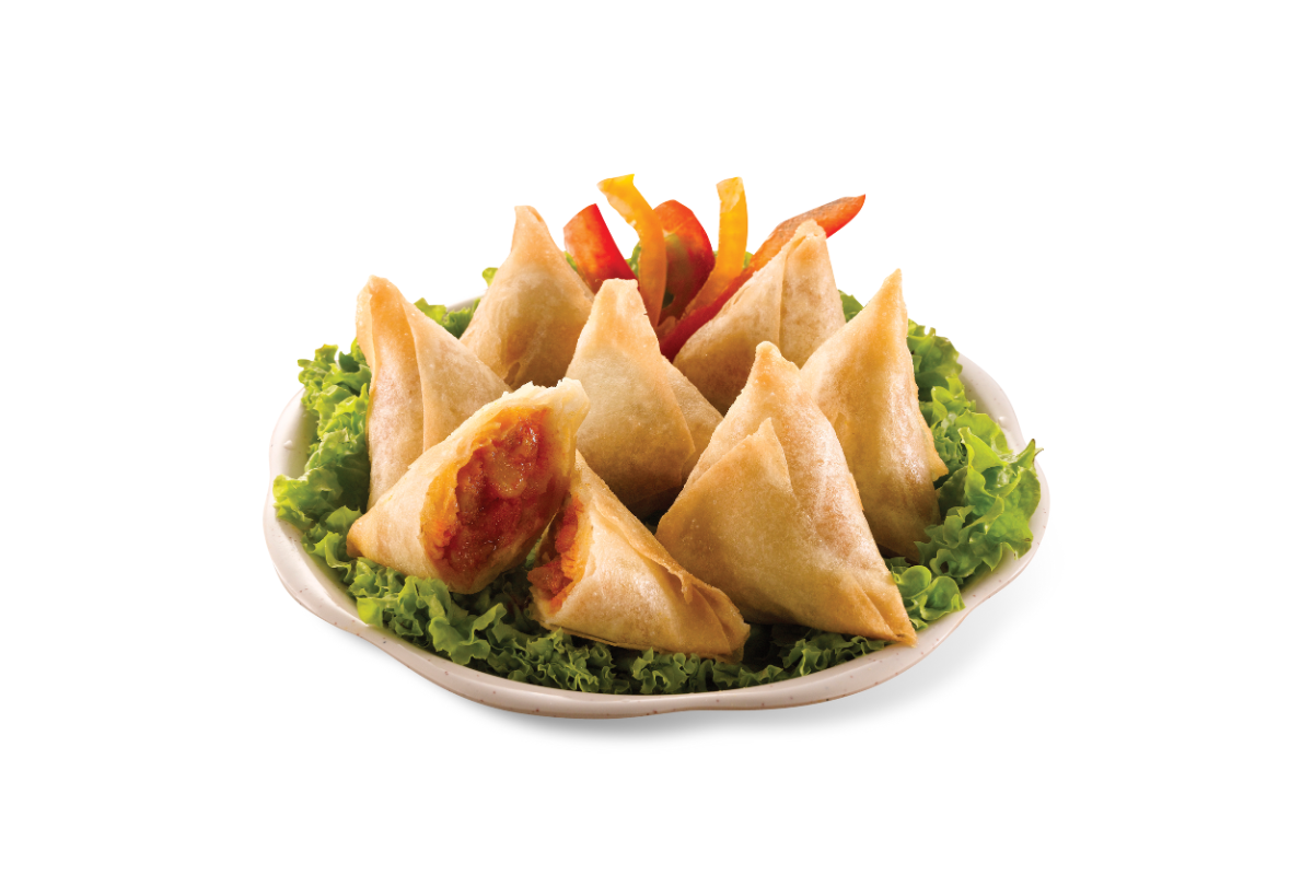 Samosas on a bed of green leaves with a white background