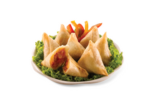 Samosas on a bed of green leaves with a white background