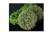Green noodles on a black plate with green leaves