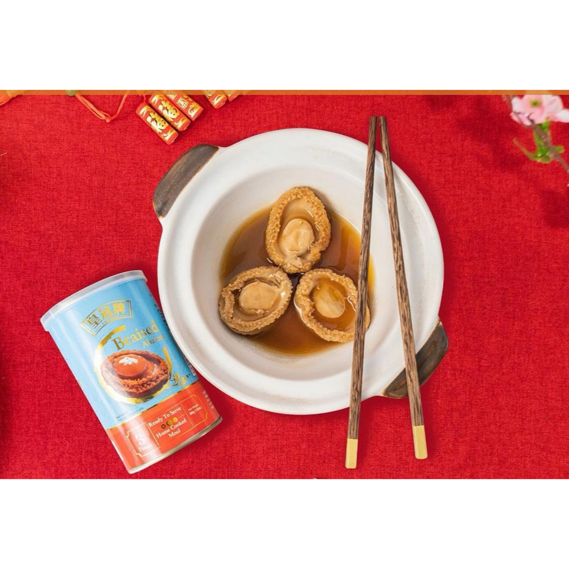 Bowl of abalone with a can and chopsticks on a red tablecloth
