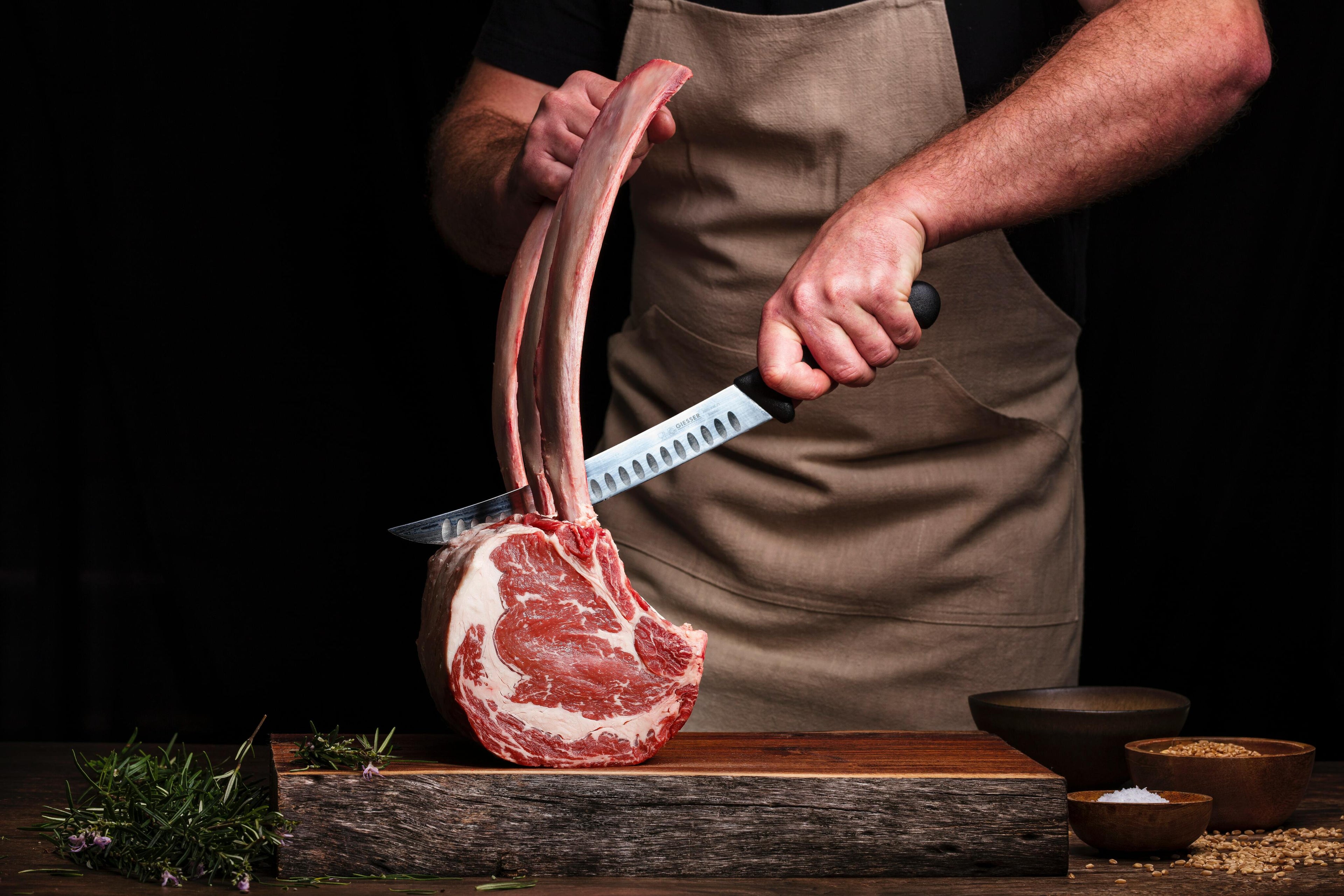 A picture of a man cutting a steak with bone