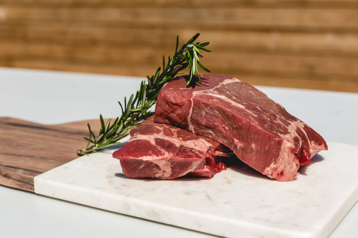 A picture of 2 raw steaks with rosemary